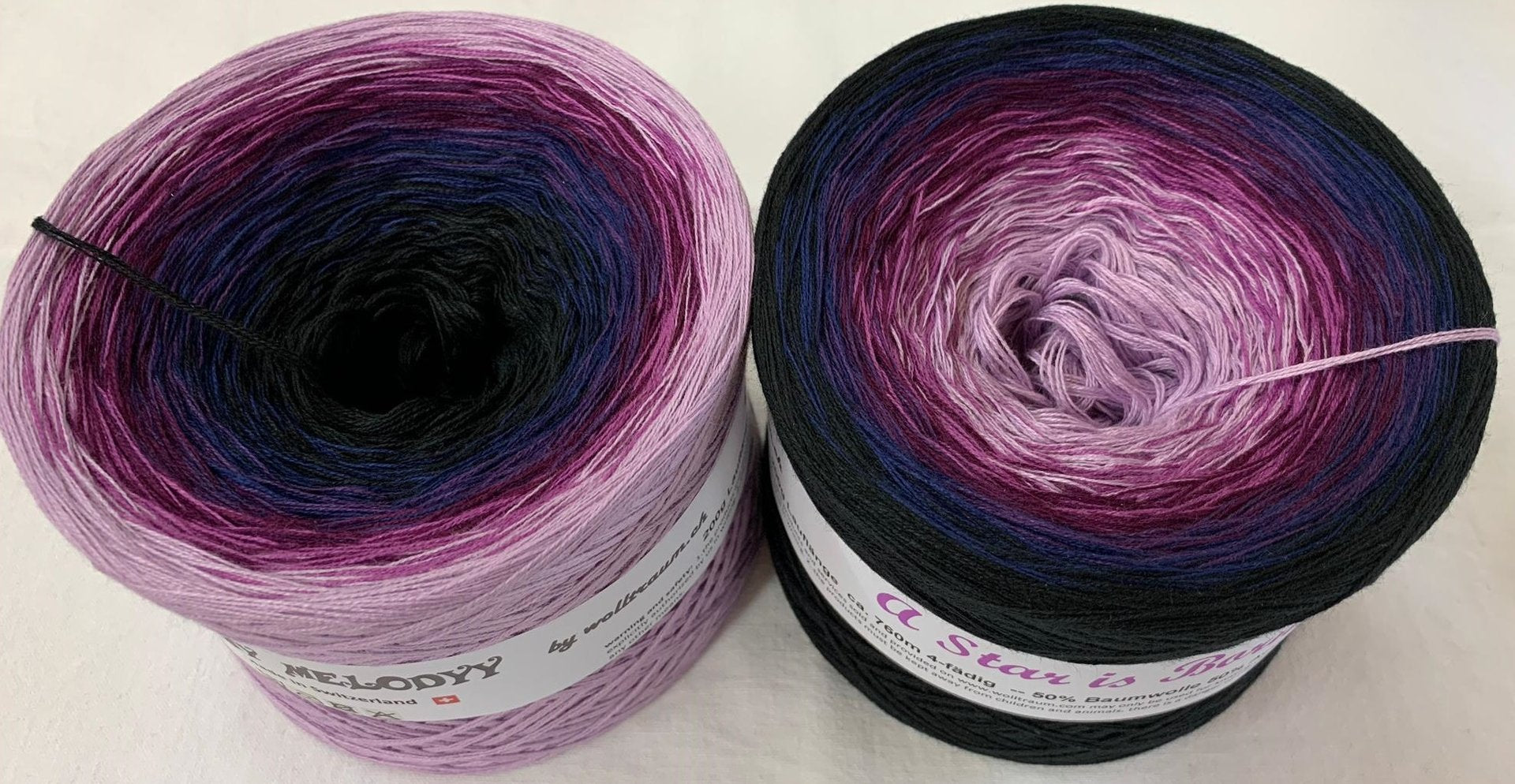 Two Wolltraum gradient yarn cakes in the colourway A Star is Born.  They go from light purple to black.