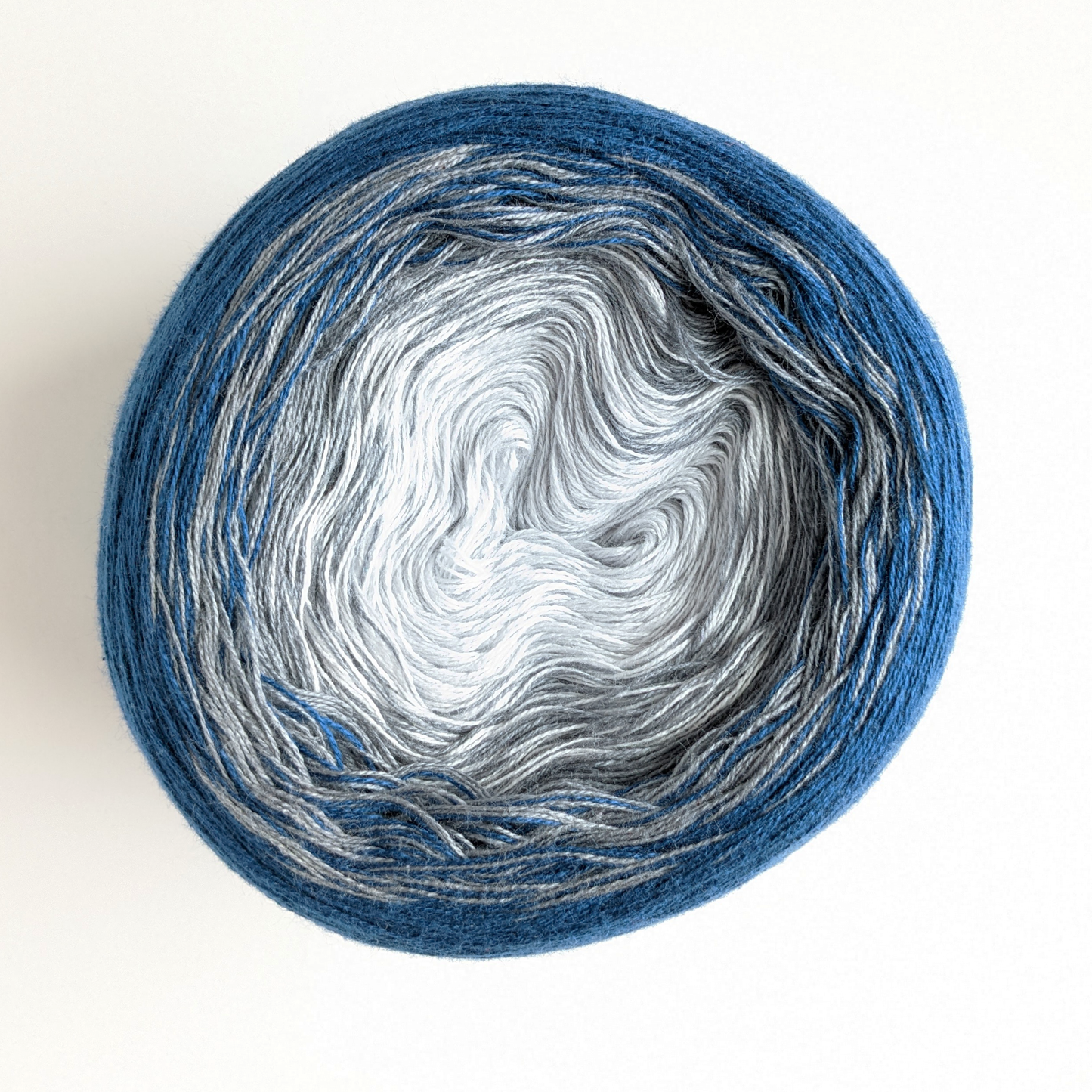 The Wolltraum gradient yarn colour Atlantis.  It includes shades of grey and a deep blue.  This cake has a light grey centre.