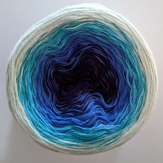 The Wolltraum My Melodyy gradient yarn colourway Azzuro with a dark centre.  This cake has an ombre effect that goes from light green to dark blue.