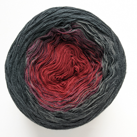 A single cake of the Wolltraum My Melodyy gradient yarn colourway Black Widow.  It goes from a deep red to black.