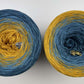 Top view of 2 cakes of the Wolltraum My Melodyy gradient yarn colourway Blue Wall.  It goes from a dusky blue to curry yellow.