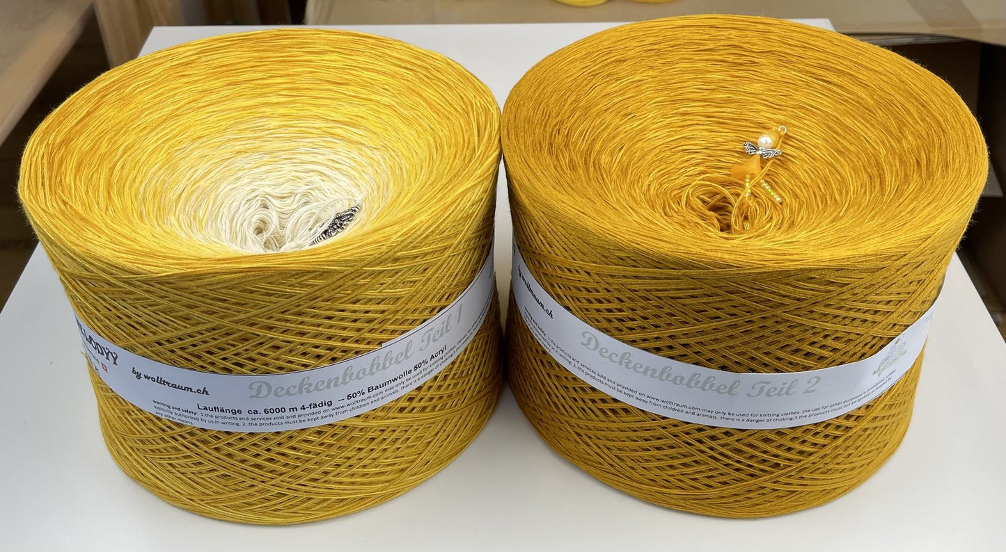 Two cakes making up a Wolltraum blanket yarn cake.  The left cake goes from cream to yellow and the right is a deep yellow.