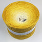 A large cake of Wolltraum yarn that goes from cream to yellow.